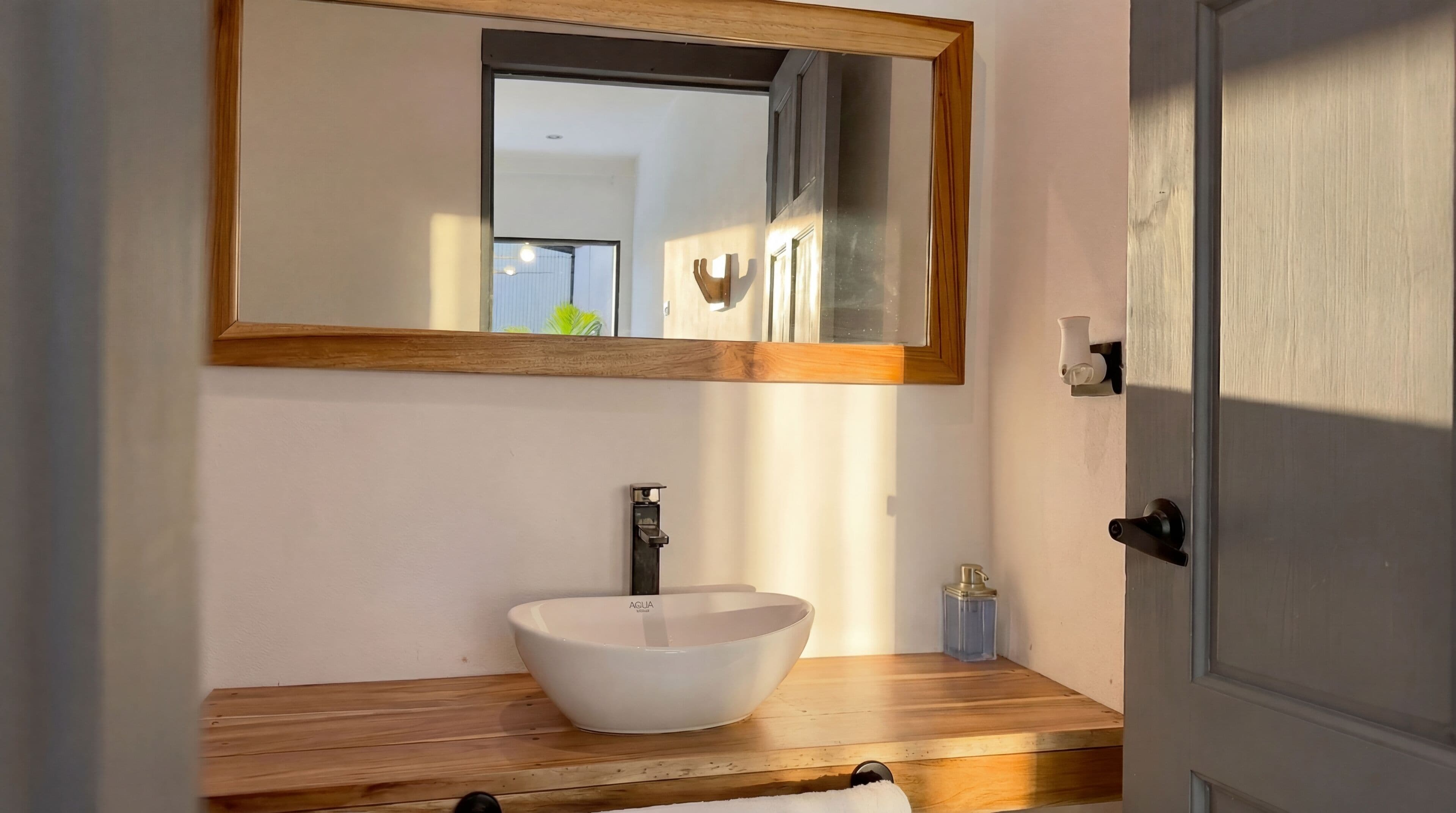 A bathroom with a wooden vanity, a white sink, and a mirror with a wooden frame.