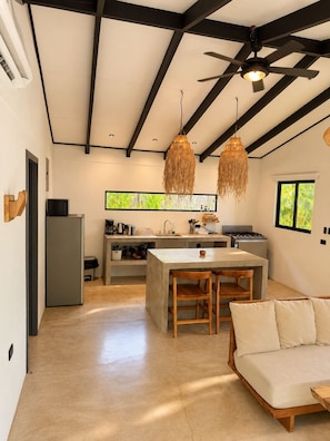 Una cocina moderna con una isla central, sillas de madera y un ventilador de techo.
