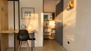 Een kamer met een bureau, stoel, ingelijste foto en een deur naar een badkamer.