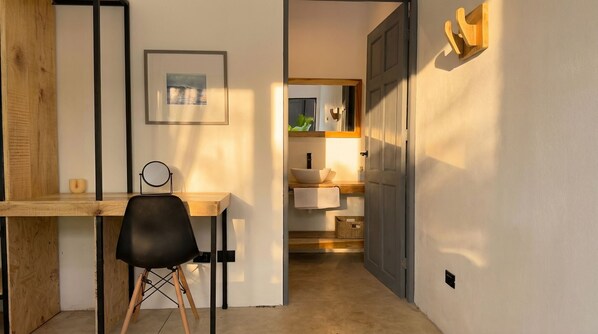 A room with a desk, chair, framed picture, and a door leading to a bathroom. - Aduana House (Cobano)