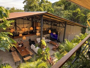 An outdoor seating area with tables and chairs, surrounded by lush greenery and a wooden pergola structure. - Aduana House (Cobano)