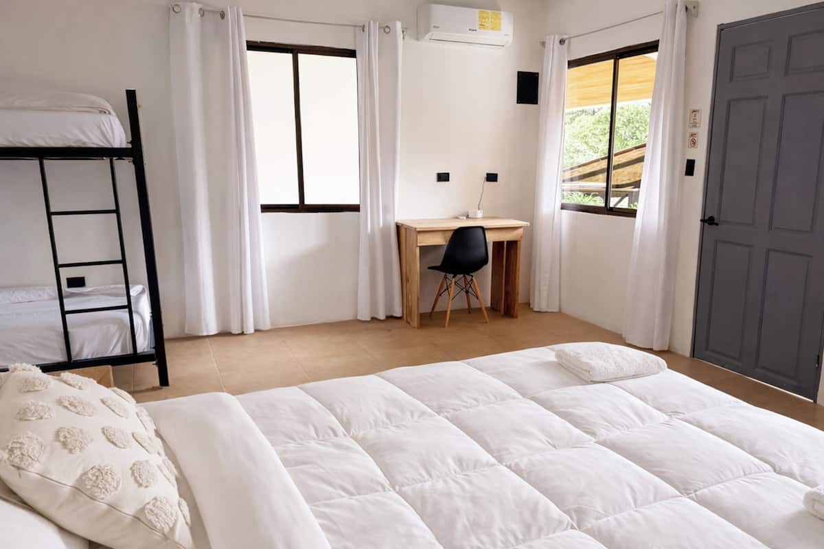 A room with a bunk bed, a desk, a chair, and a door.