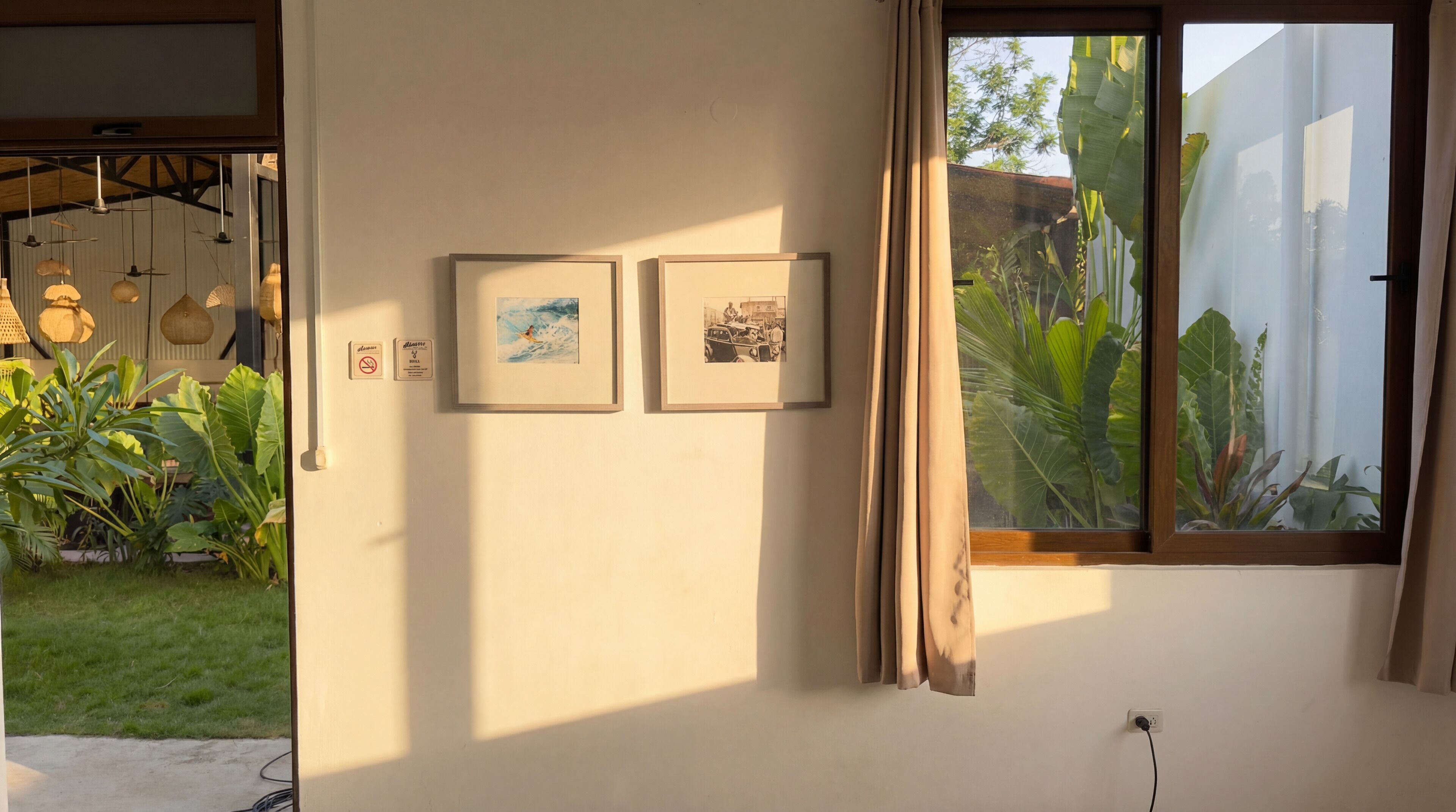 Une pièce avec une fenêtre, deux tableaux encadrés au mur et une prise de courant.