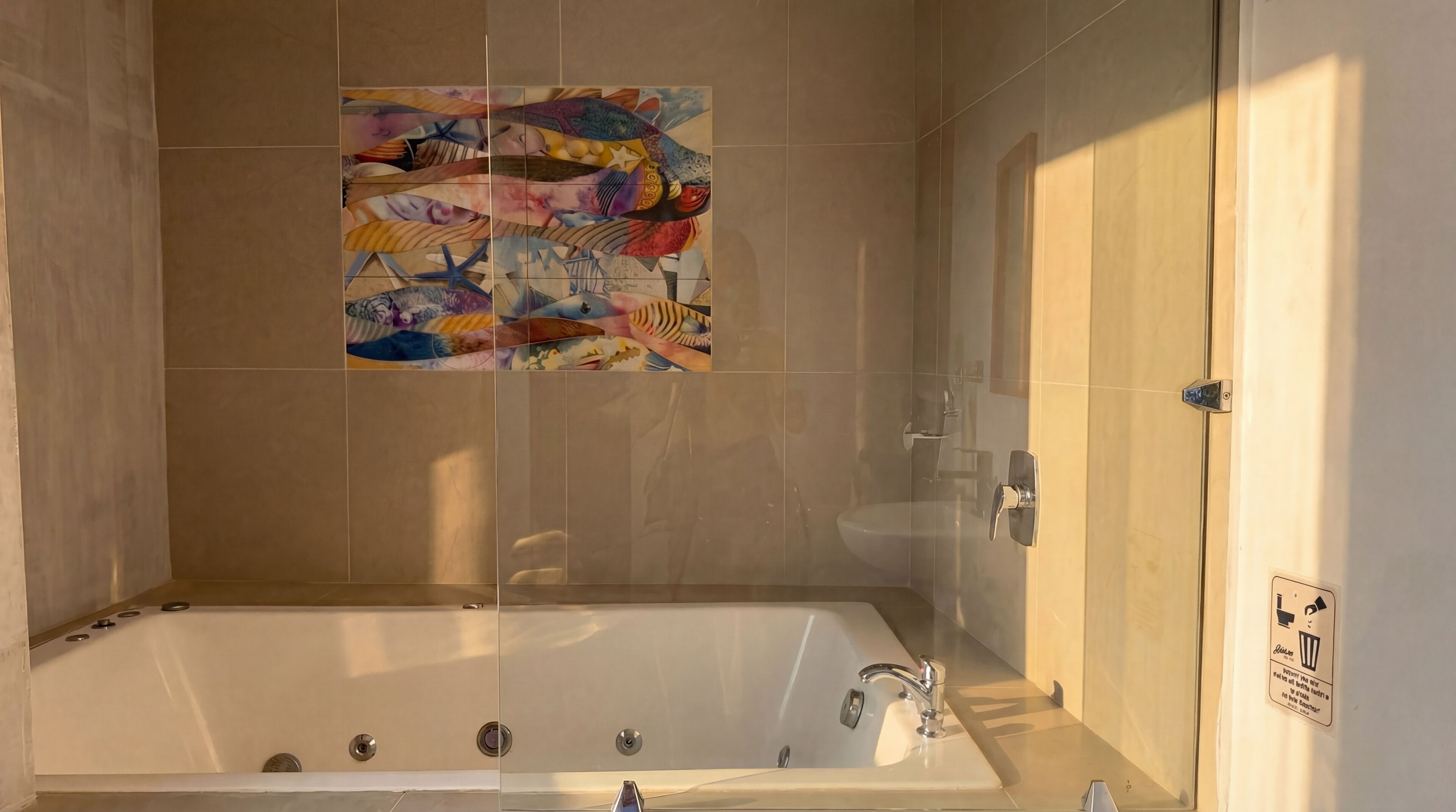 A bathroom with a bathtub, a toilet, and a shower. There is a colorful artwork on the wall.