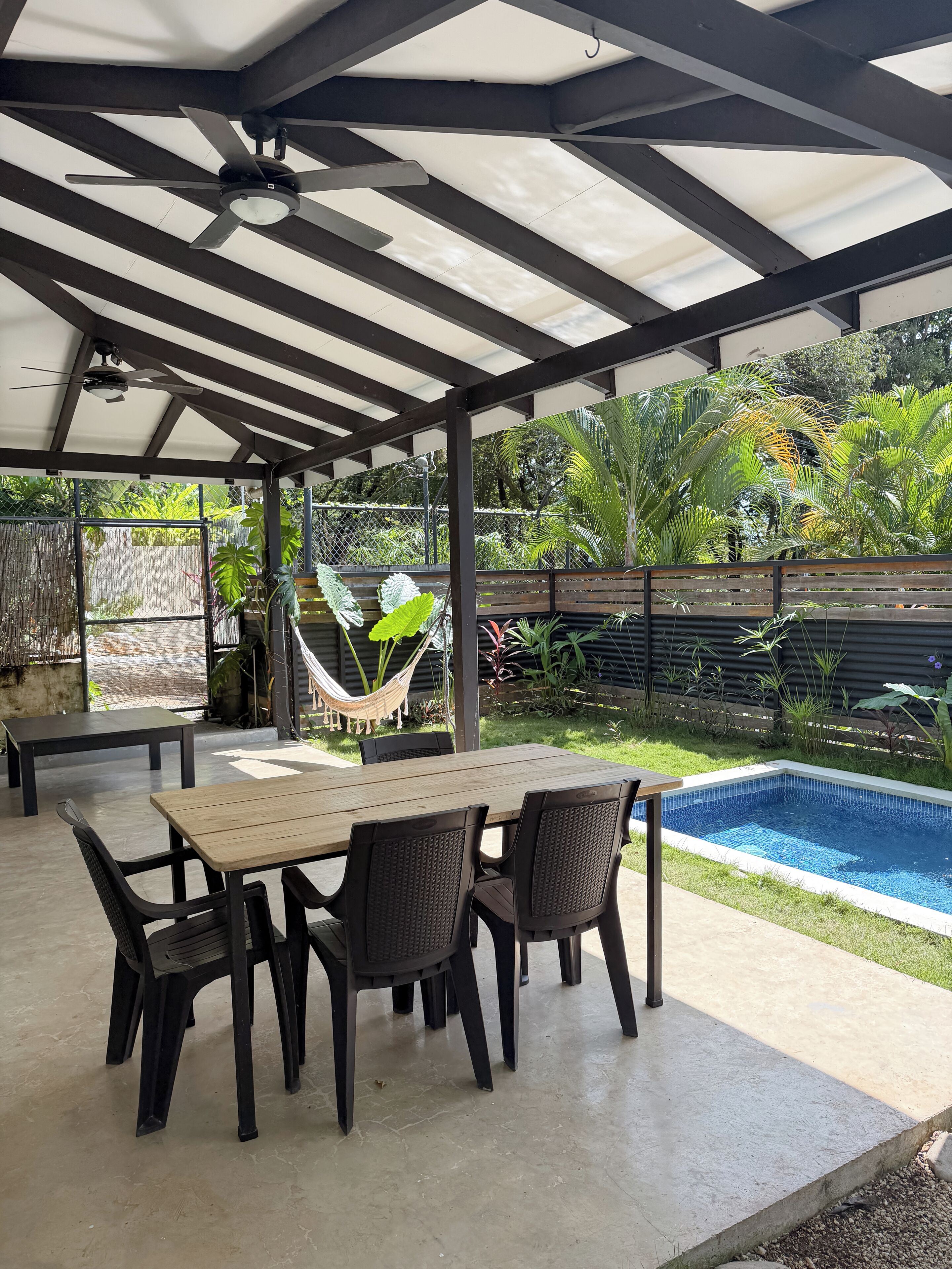 A covered patio area with a pool, outdoor furniture, and a hammock.