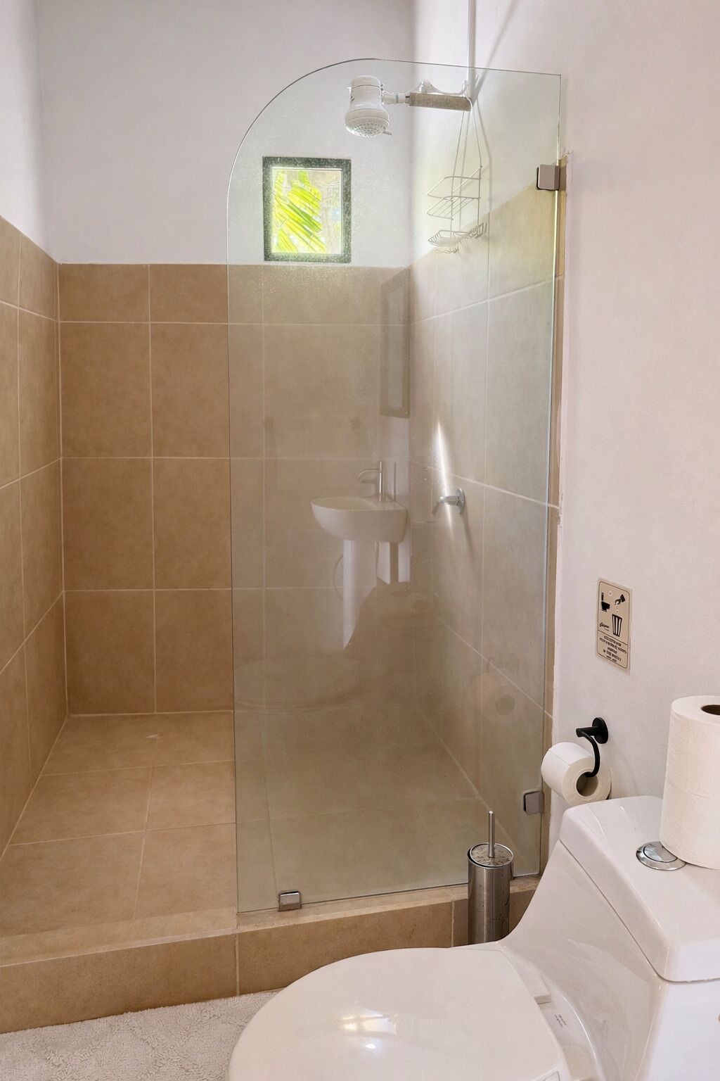 A bathroom with a glass shower enclosure, a toilet, and a sink.