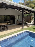 Um alpendre coberto com piscina, área de estar ao ar livre e rede.