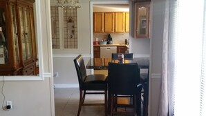 Un comedor con una mesa y sillas, una cocina al fondo, y piso alfombrado.