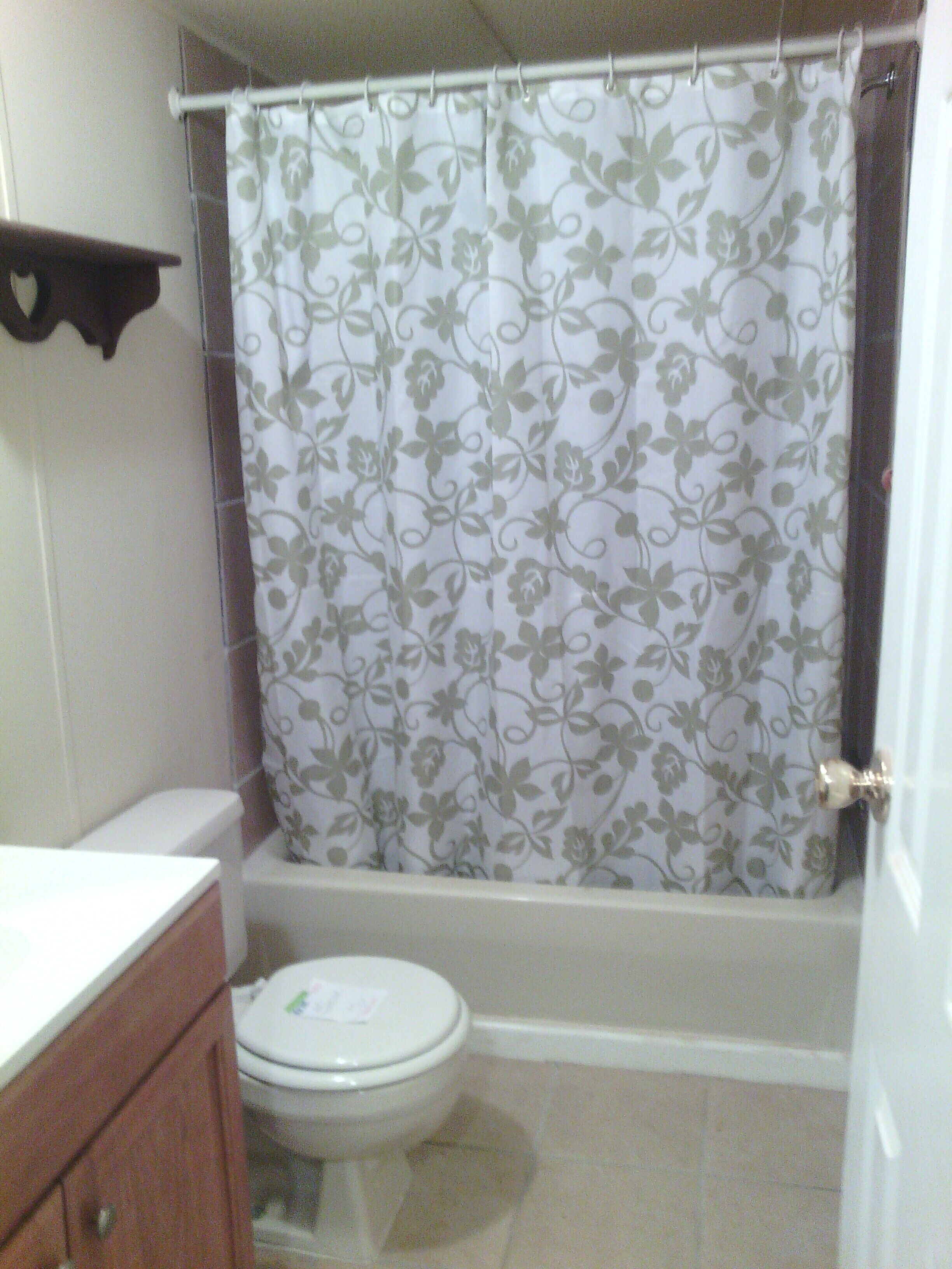 Ein Badezimmer mit Toilette, einer Duschvorhang mit Blumenmuster und einem Holzkabinent.