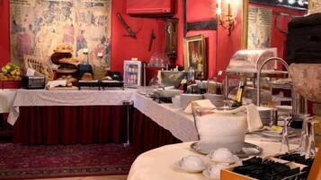 Un comedor con montaje tipo bufé, que incluye un pastel grande, diferentes opciones de comida y una estación de bufé con utensilios.