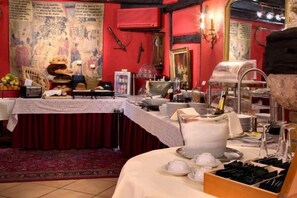 A dining area with a buffet setup, including a large cake, various food items, and a buffet station with utensils. - Hôtel Le Maréchal (Colmar)