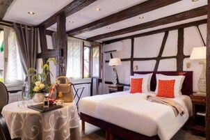 Habitación de hotel con una cama grande, un escritorio con silla, una mesa con un florero y una ventana con cortinas.