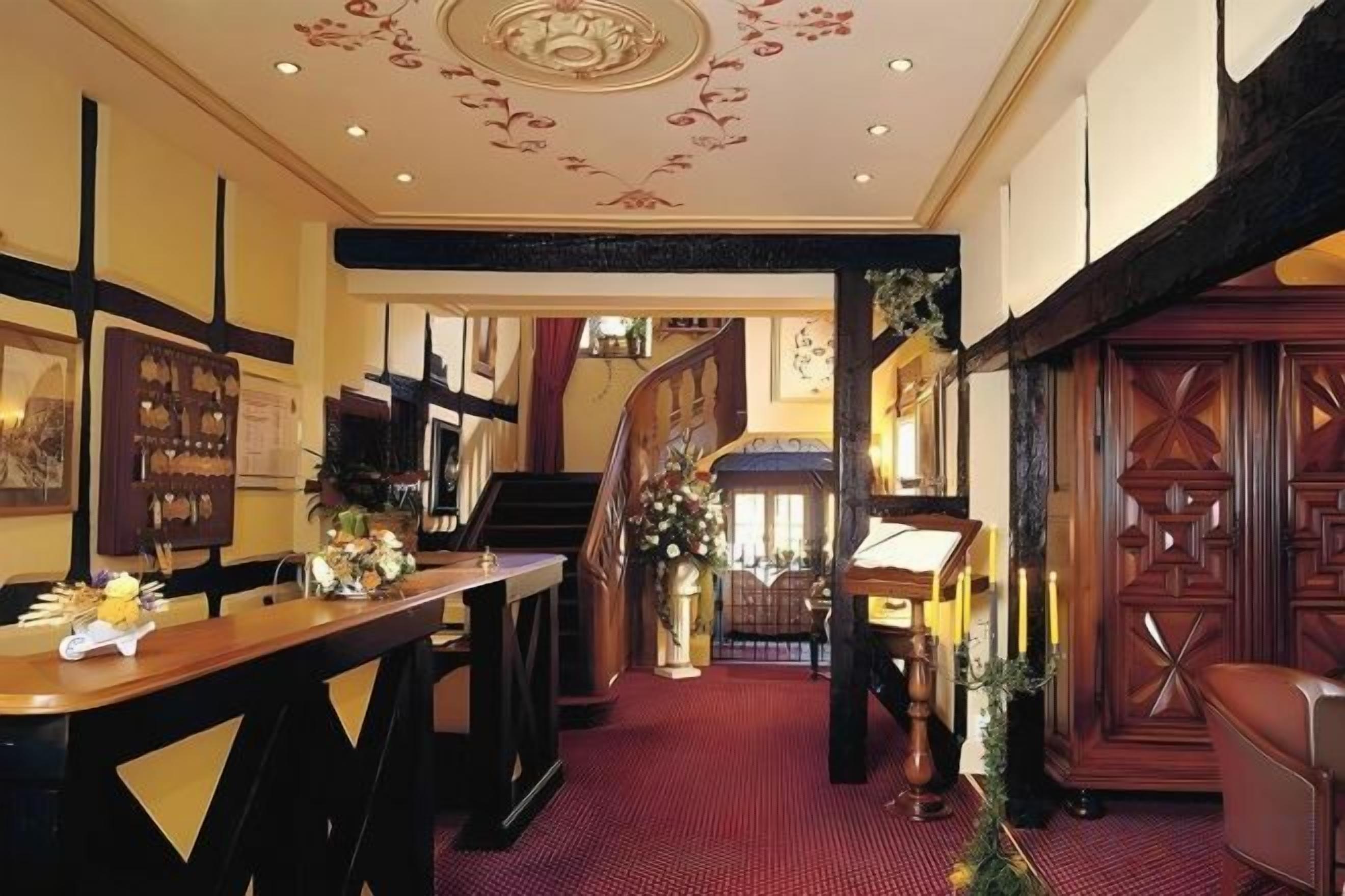 Un vestíbulo de hotel con una escalera, una recepción y un comedor.