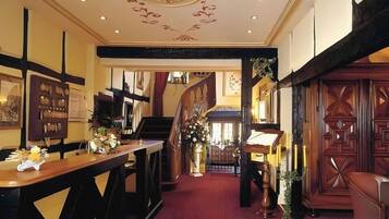 Un vestíbulo de hotel con una escalera, una recepción y un comedor.