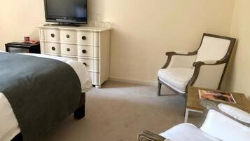 Habitación de hotel con una cama, un televisor en una cómoda, una silla y una mesita con una revista.