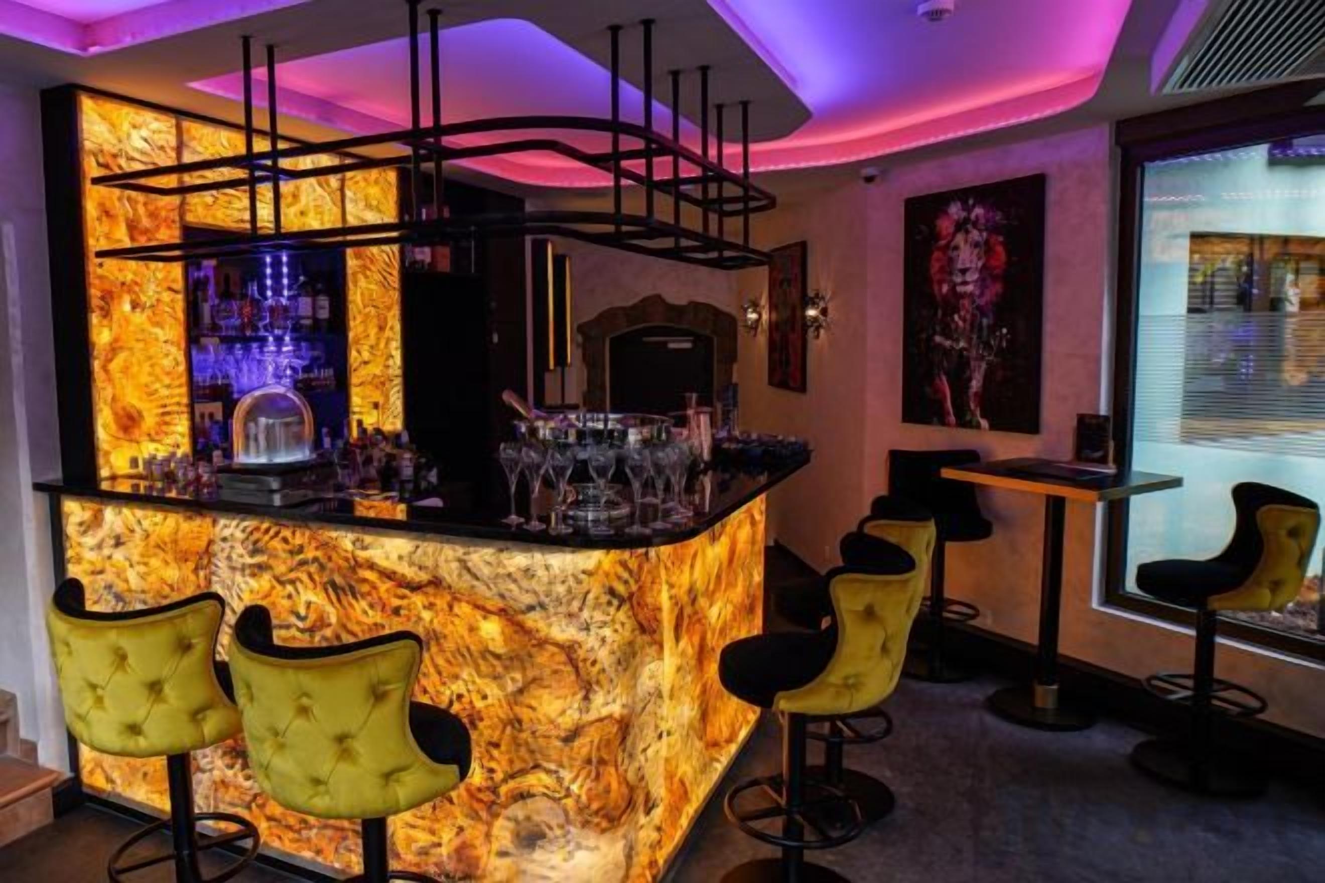 A bar area with a marble countertop, bar stools, and a seating area with a view.