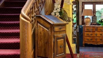 Um armário de madeira com gavetas, uma escada com corrimão de madeira e um tapete estampado no chão.