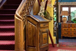 Un mueble de madera con cajones, una escalera con barandal de madera y una alfombra estampada en el suelo.