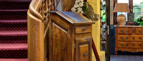 Un mueble de madera con cajones, una escalera con barandilla de madera y una alfombra estampada.