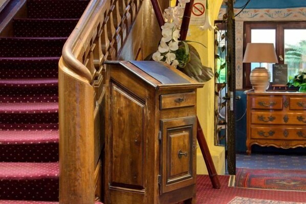 A wooden cabinet with drawers, a staircase with a wooden handrail, and a patterned carpet. - Hôtel Le Maréchal (Colmar)