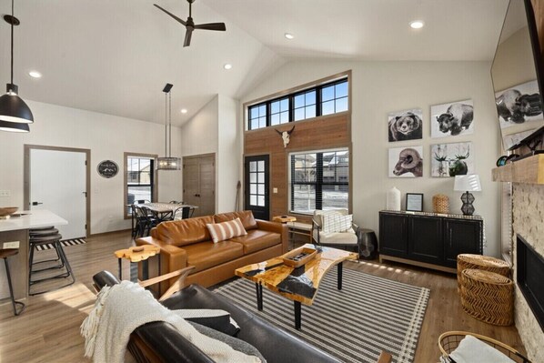 A spacious living room with a large window, a fireplace, and a dining area.