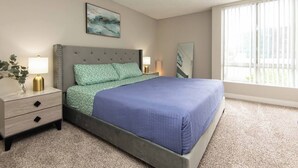 A bedroom with a bed, nightstands, a lamp, a mirror, and a painting on the wall.