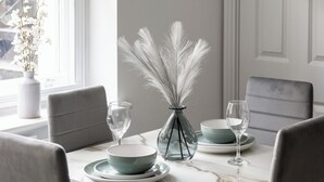 A dining table set with plates, bowls, and a vase with white flowers.