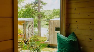 A wooden cabin with a window seat overlooking a pond and trees.