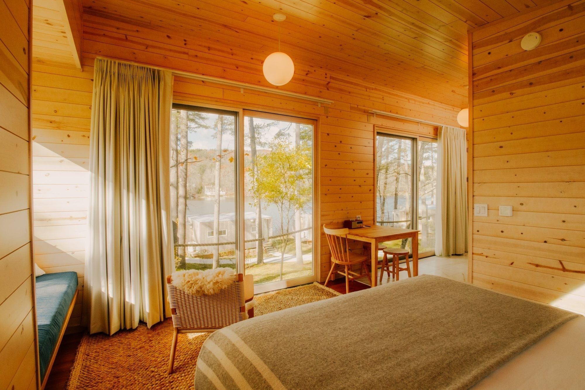 A wooden cabin room with a bed, a table, and chairs.