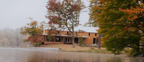 A wooden boat on calm water with a house in the background.