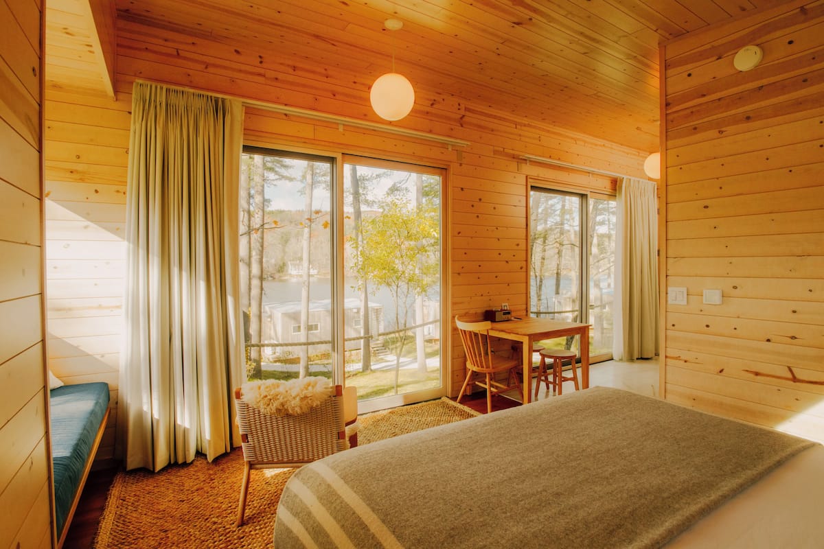 Ein Zimmer in einer Holzhütte mit einem Bett, einem Tisch und einem Stuhl.
