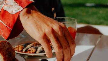 A person serving figs on a white table with a glass of drink and bread.