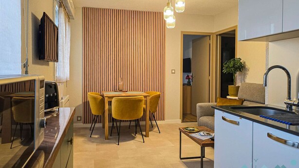 A compact kitchen with a dining area, a sofa, and a small table.