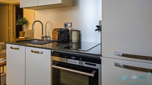 A compact kitchen with a built-in oven, a coffee maker, and a sink.
