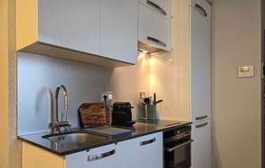 Een compacte keuken met een spoelbak, fornuis en oven, voorzien van moderne apparatuur en een klein aanrecht.