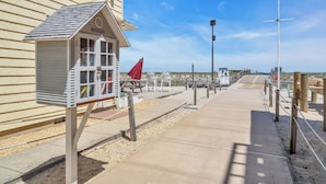 A beachside walkway with a lifeguard tower, benches, and a clear sky.