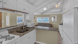 A kitchen with white cabinets, a granite countertop, a built-in microwave, and a refrigerator.