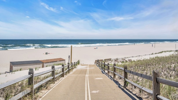 A wooden boardwalk leading to a beach with a clear sky.