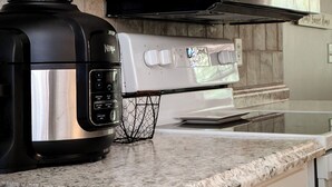 Una cocina con armarios blancos, una campana extractora de acero inoxidable y una encimera negra.