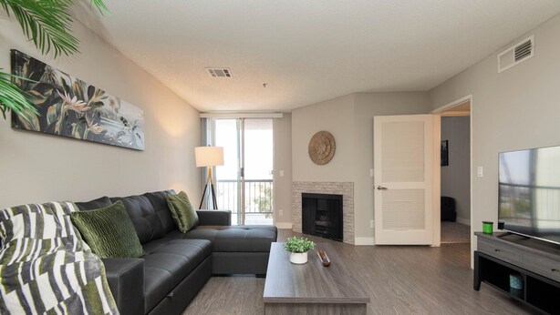 A modern living room with a sectional sofa, a coffee table, a flat-screen TV, and a fireplace.