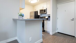 A modern kitchen with white cabinets, a stainless steel refrigerator, and a microwave.