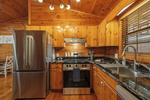 A kitchen with wooden cabinets, a stainless steel refrigerator, a gas stove, and a sink. - The Crow’s Nest: Pet-friendly, Privacy, Mountain Views, Fire Pit & Deck! (Blue Ridge)