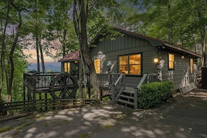 A cabin with a large wheelhouse, wooden deck, and a view of the landscape.