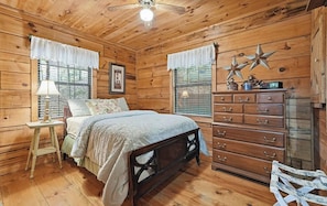 A wooden cabin bedroom with a bed, dresser, and a star decoration on the wall.