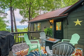 Una terraza con mobiliario exterior, una chimenea y vistas a las montañas.