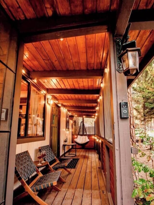 Eine Holzterrasse mit hängenden Lichtern, Sitzgelegenheiten im Freien und einem Hängesessel.