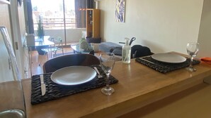 A dining area with a table set for two, a bottle of hand sanitizer, and a painting on the wall. - The best location in Santiago, in the heart of the golf neighborhood, MUT, Costanera Ctr. (Las Condes)