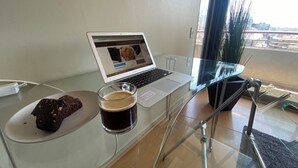 A laptop on a glass table with a glass of dark liquid and a piece of chocolate on a plate. - The best location in Santiago, in the heart of the golf neighborhood, MUT, Costanera Ctr. (Las Condes)