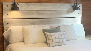 A bed with a wooden headboard, white bedding, and two wall-mounted lamps. - Private, secluded 2-bedroom house with King, Queen beds near Cable with WiFi, AC (Cable)