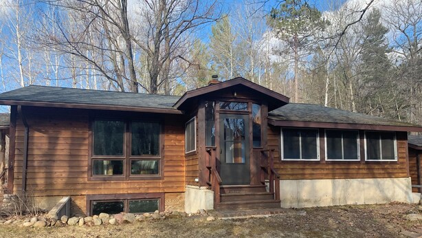 A wooden cabin with a front porch, large windows, and a stone foundation. - Private, secluded 2-bedroom house with King, Queen beds near Cable with WiFi, AC (Cable)